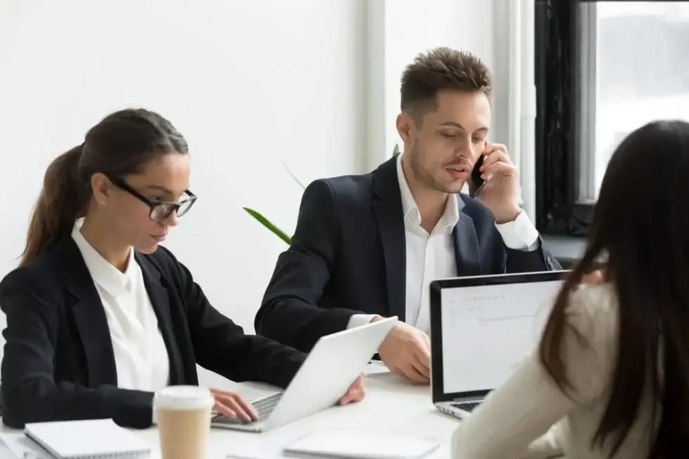executive-business-people-using-laptops-work-talking-phone-scaled-1-1 Employees working on laptops during a collaborative office meeting